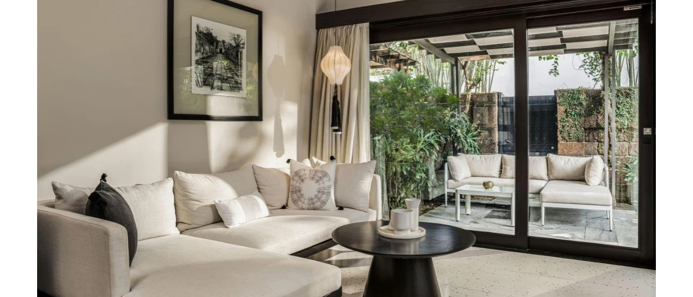 Stylish villa living area, with a white sofa, black coffee table and patio doors that showcase an outdoor sofa and table in a walled courtyard