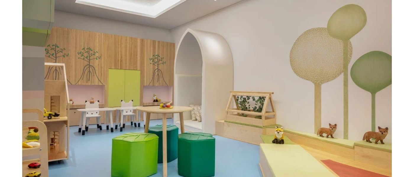 Children's club room with cabinets with tree stencils, green stalls, wooden tables and chests and decorative foxes