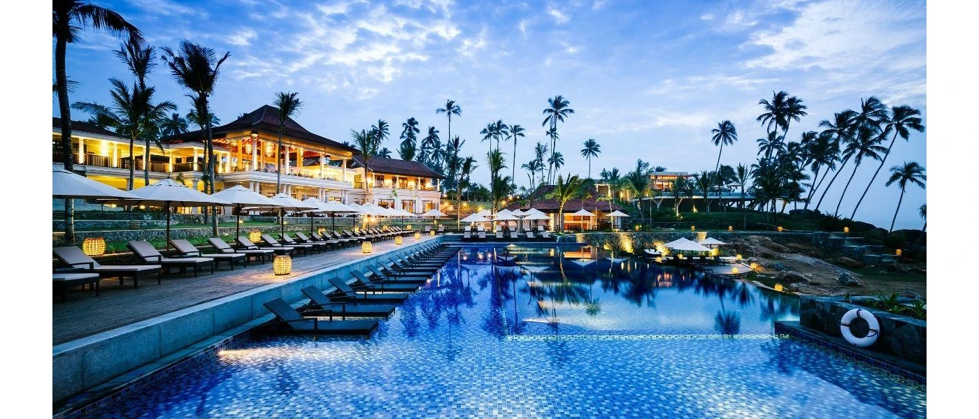 Swimming pool after dark, showing in-water loungers and the lights from the surrounding buildings