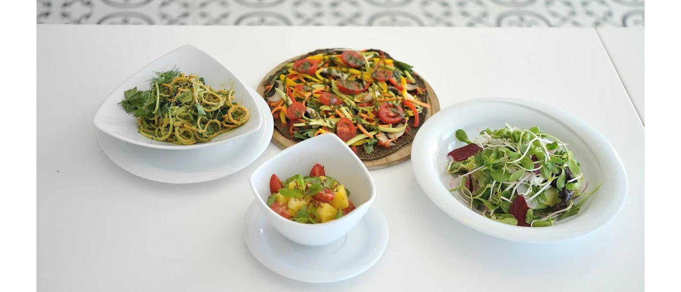 White bowls containing fruit, salad, vegetables and a spaghetti 