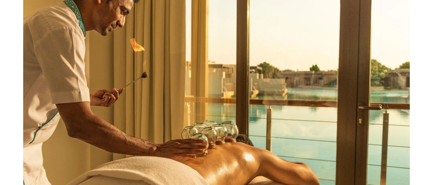 Therapist performs cupping in a spa therapy session in a room with a pool view