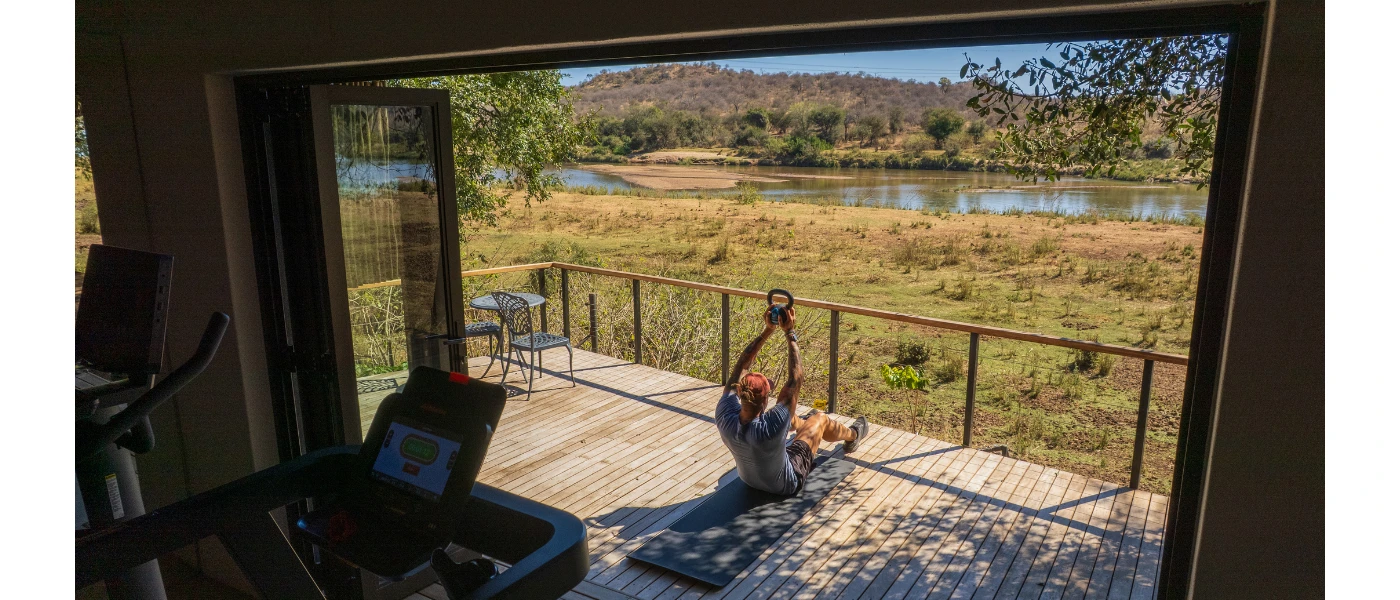 Man works out on a wooden deck with views of the African greenery and river