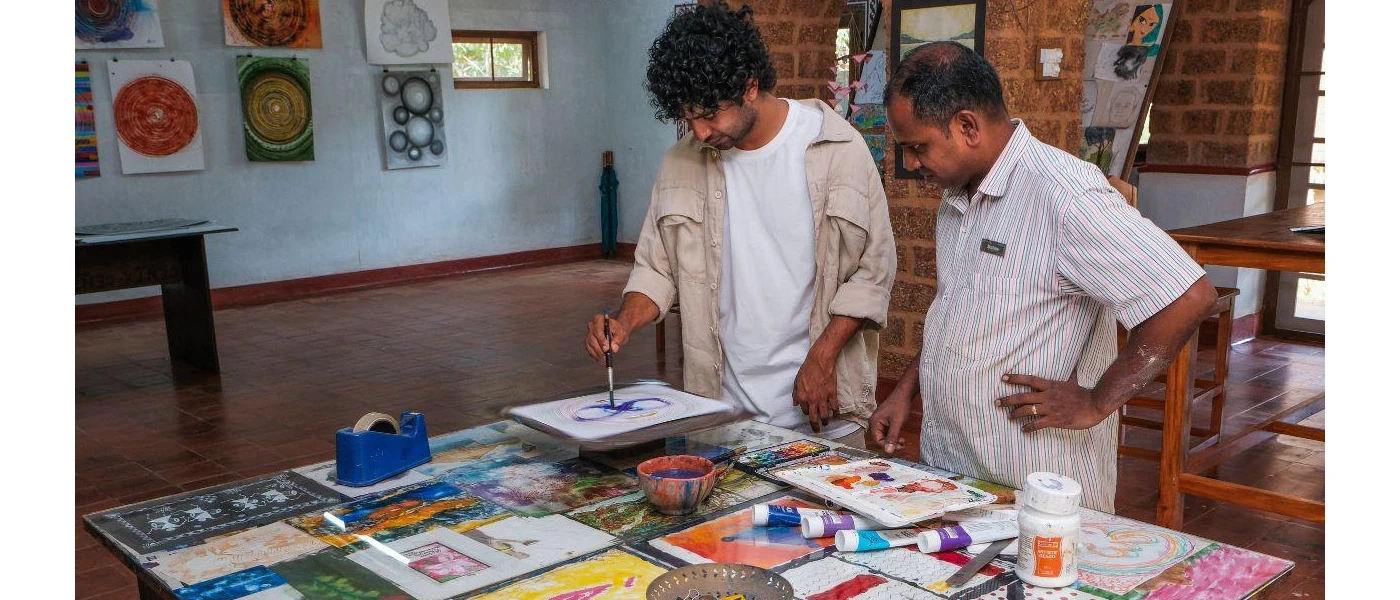 Male guests doing a painting at the studio and supervised by the member of the arts team