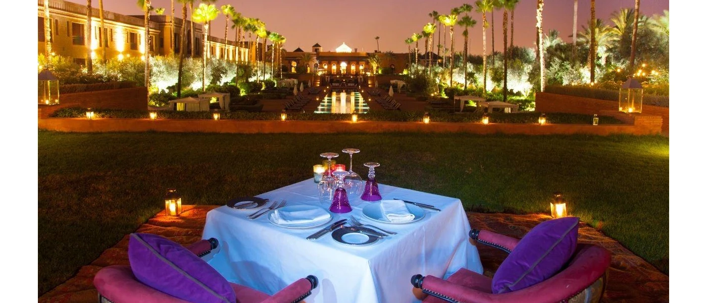 Dinner table set up after dark with candles and a view of landscaped grounds