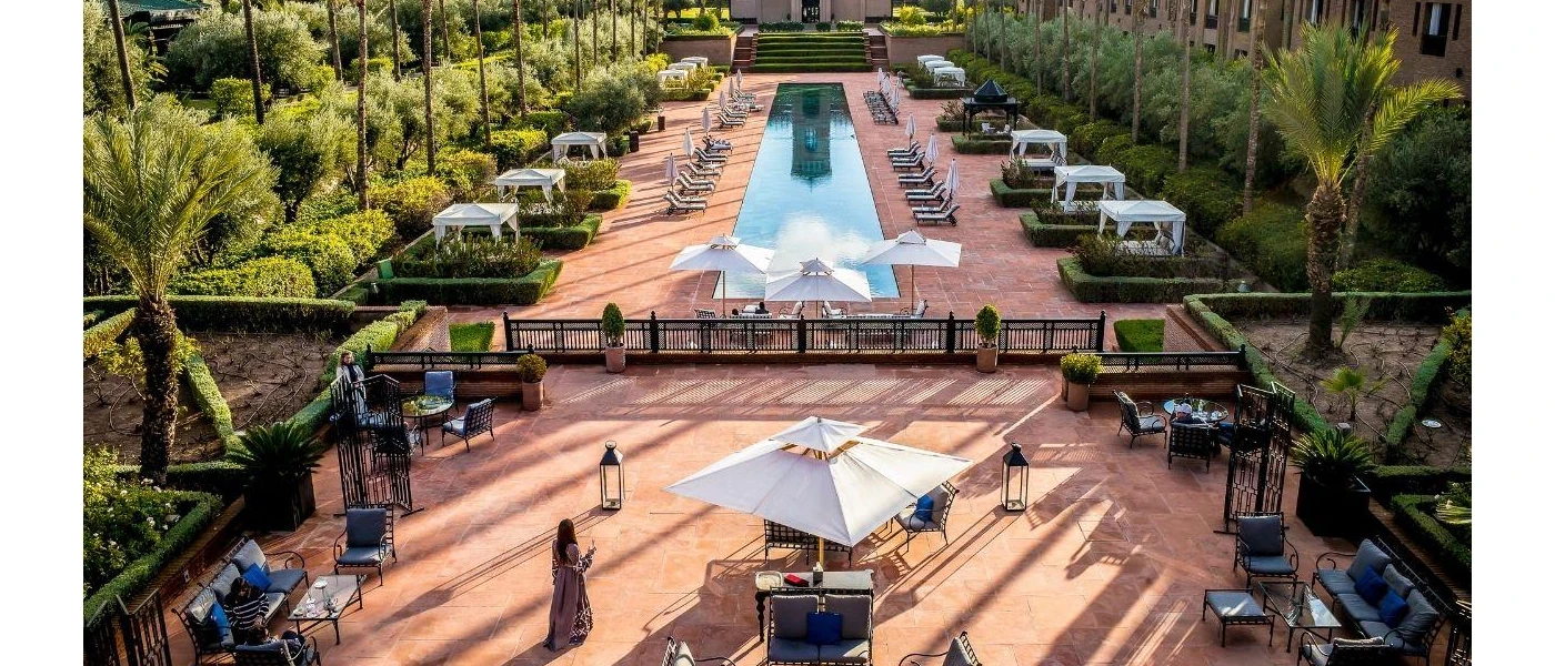 Swimming pool surrounded by daybeds with white curtains and greenery