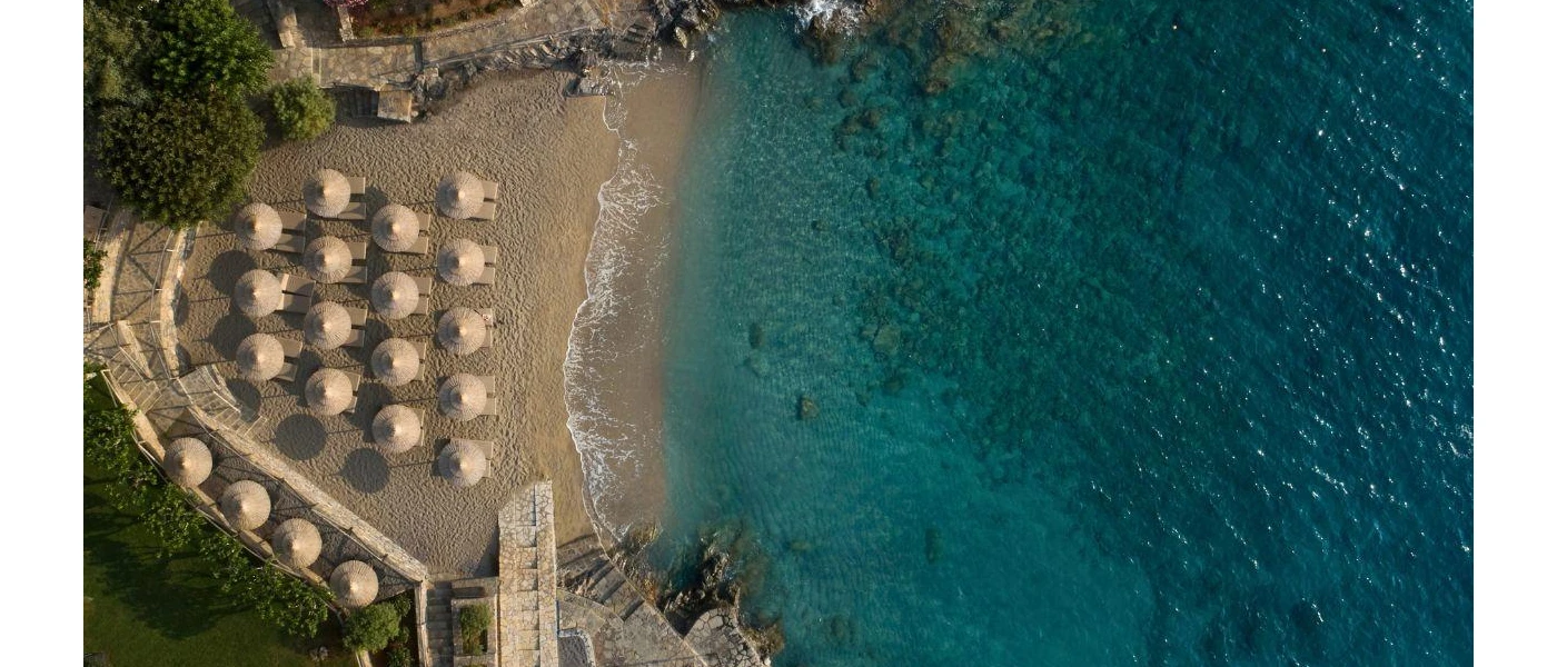 Vanilla-coloured sandy cove lapped by turquoise waters, lined with thatched parasols and loungers
