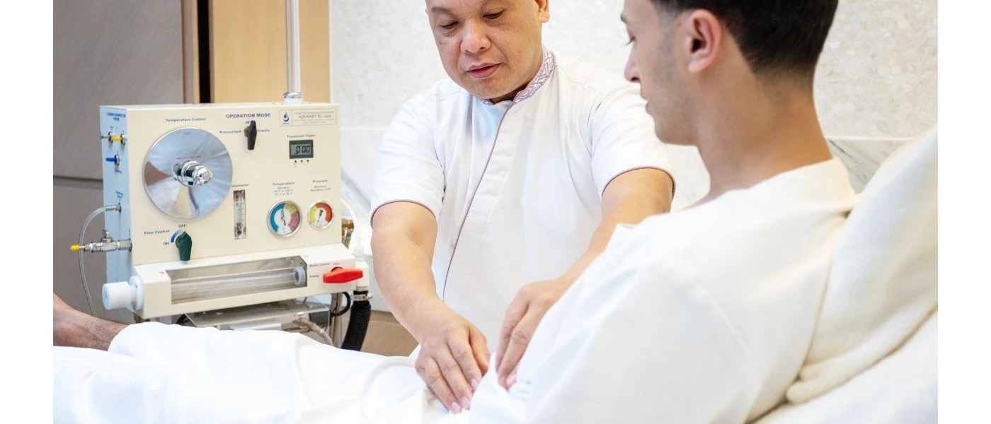 Staff member in white uniform assesses a man lying on a bed, hooked up to a clinical-style machine behind