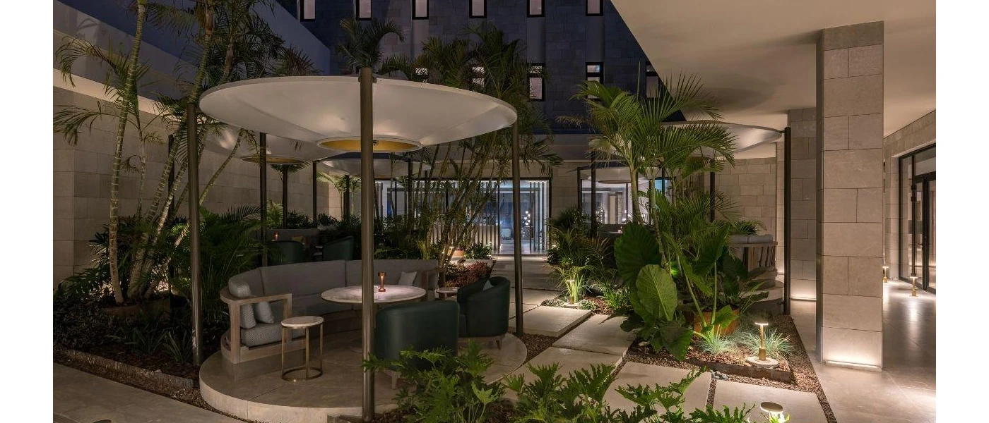 Outdoor courtyard filled with plants and a cosy covered seating booth, with tables for drinks