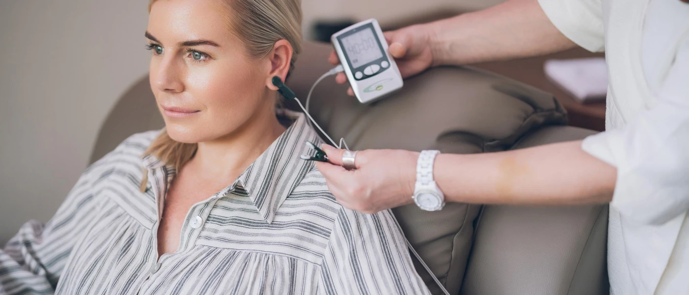 Staff member takes a reading from a device inserted into a woman's ear