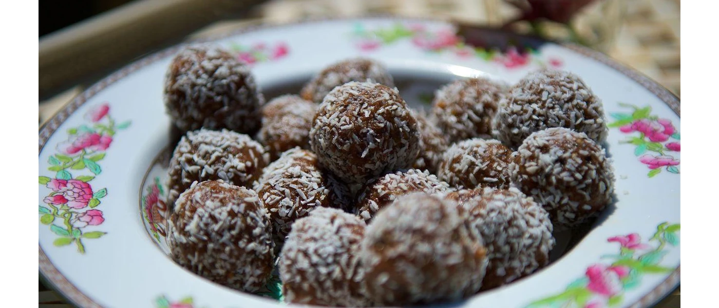 Protein balls coated in coconut shavings in a delicate china bowl