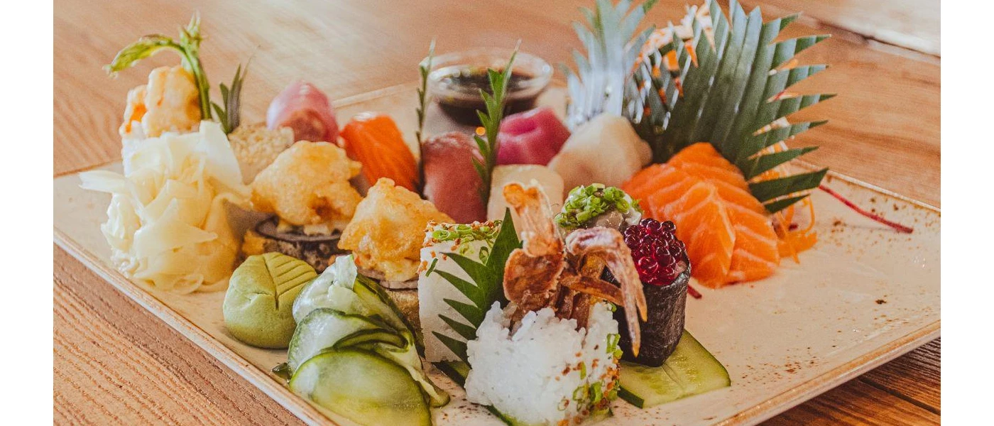 Tray of sushi with foliage garnish, including salmon nigiri and caviar
