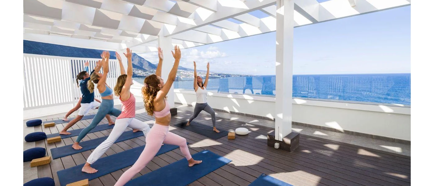 Women in active wear practising yoga in a sea-facing studio