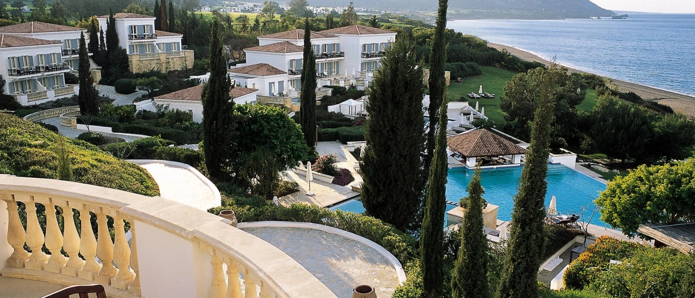 Whitewashed, terracotta-roofed buildings, cypress trees and a swimming pool overlooking the sea and surrounding hills