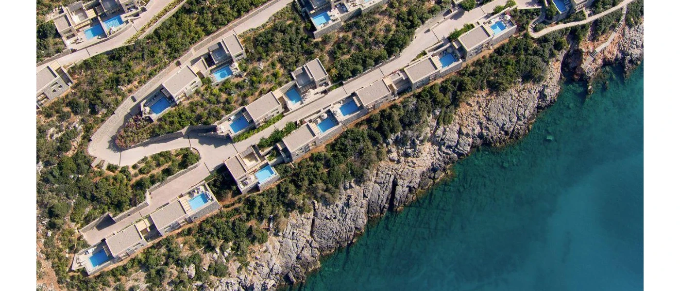 Low-rise villas with private pools on a rugged hillside overlooking the sea
