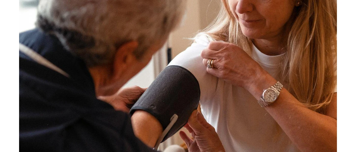 Medical professional taking the blood pressure of a woman with blonde hair