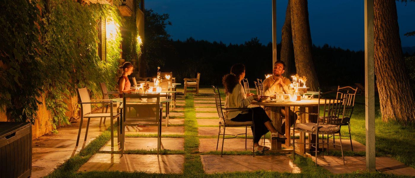 Outdoor terrace at night with candle lit tables and people having dinner 