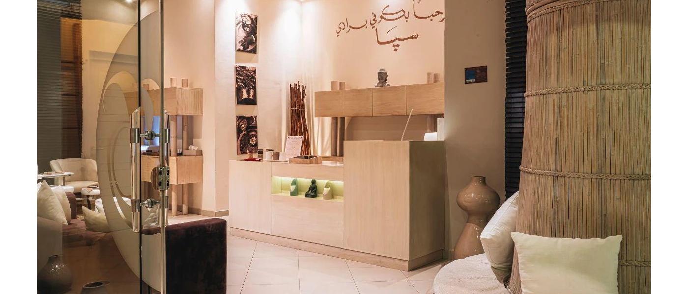 Neutral room with ivory cushions, rattan wall effect and reception desk with Arabic writing above