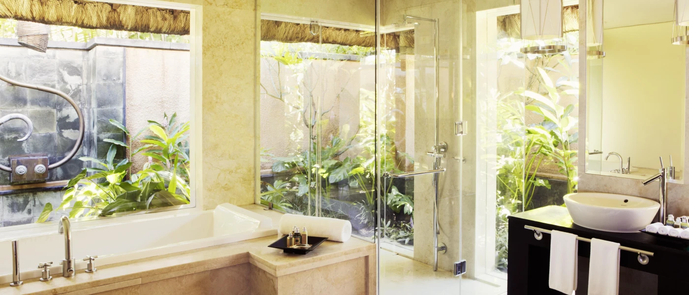 Luxury bohemian-style bathroom with full-length windows, a marble bathtub and black vanity unit