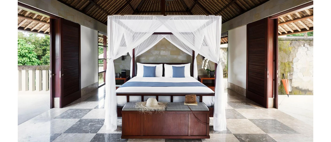 Bedroom with dark-wood sliding doors, beamed ceilings and a four-poster bed draped in sheer white fabric