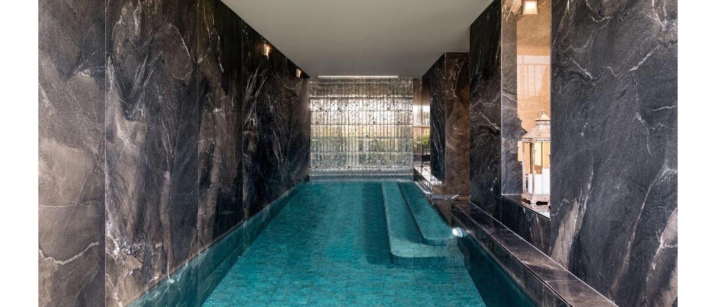Indoor pool with dark grey marble-like walls and lanterns to one side