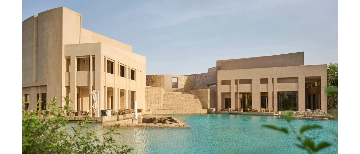 Cube-like modern buildings in sand colours next to a swimming pool
