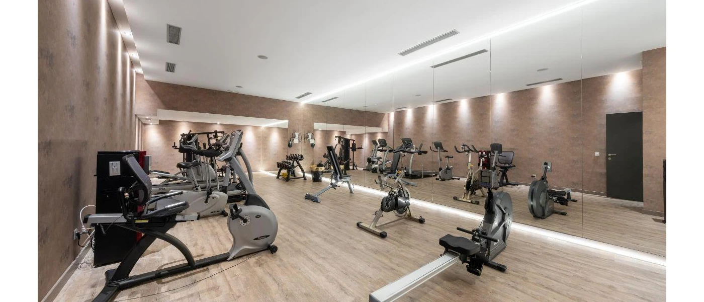 Gym with a wall of full-length mirrors, a rowing machine, bikes and treadmills