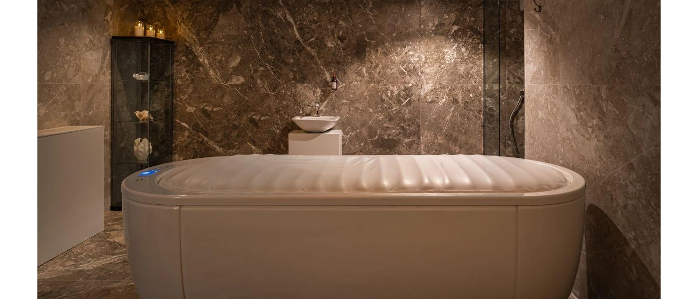 Spa treatment room with dark grey marble-like walls, a large medical chamber and a wooden chest with candles on top