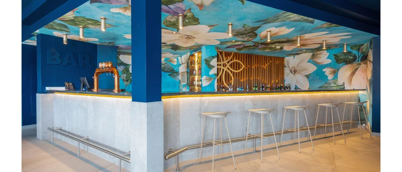 Bar with a floral painted ceiling mural with white flowers and a blue background, dark blue columns and a grey bottom
