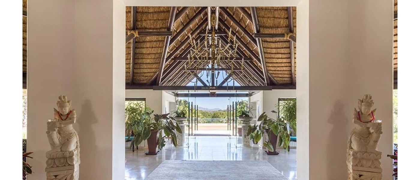 Lobby with marble floors, a wood-beamed ceiling, rustic chandelier with candlestick design and wooden arms, and Hindu statues