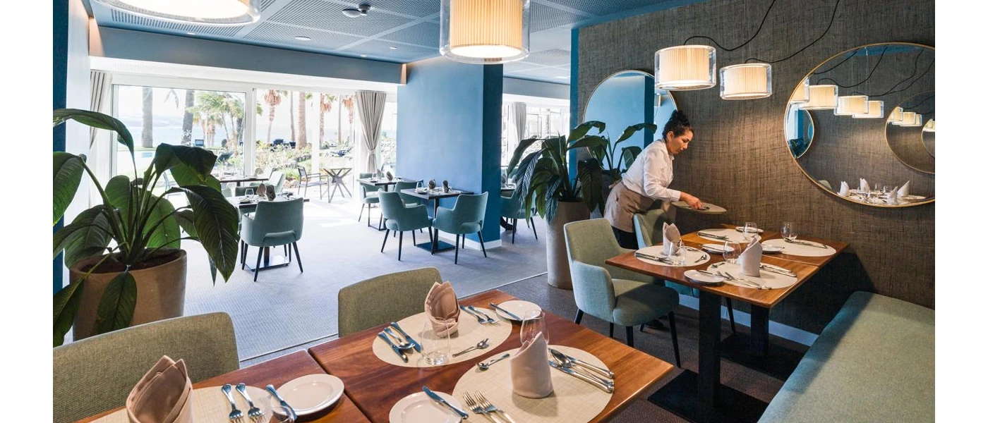 Waitress laying out tables in a restaurant with contemporary lighting and plants