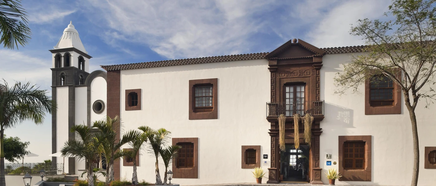 Elegant exterior of Hacienda del Conde, a luxury resort in Tenerife surrounded by palm trees
