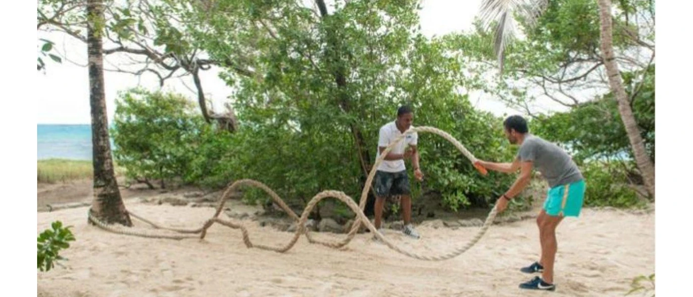 Two men using rope to keep fit on the beachfront
