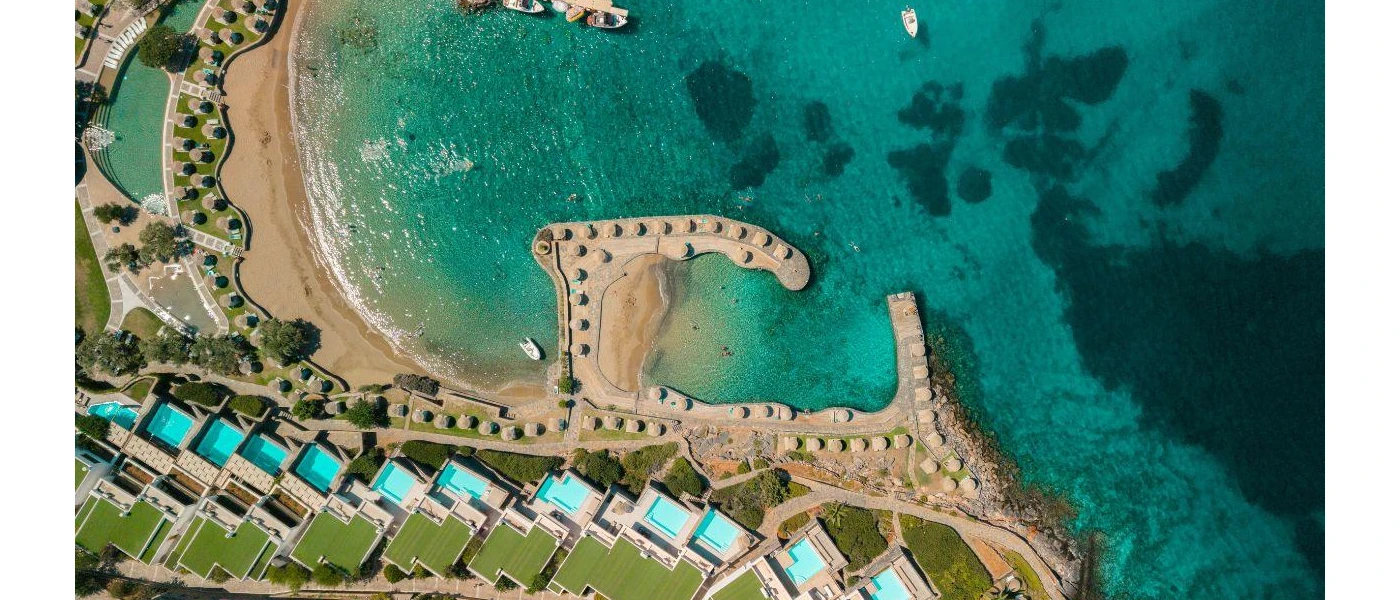 Aerial view of Porto Elounda Golf & Spa Resort, next to a dreamy blue sea