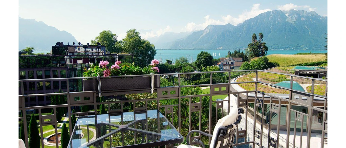 Iron balcony overlooking manicured gardens, lawns and mountains
