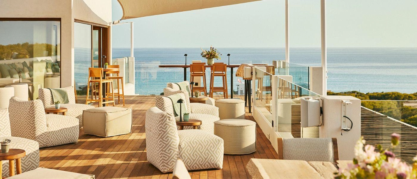 Sea-facing rooftop with wooden decking, neutral plush seating and wooden stalls
