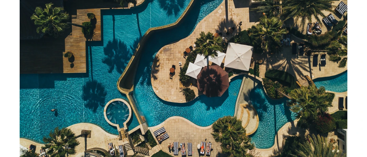 Lagoon-like pools seen from the air in landscaped grounds peppered with palm trees