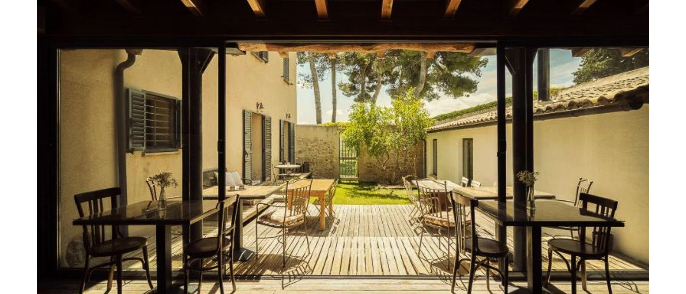 Outdoor terrace with wooden decking, wooden tables and chairs and a garden view