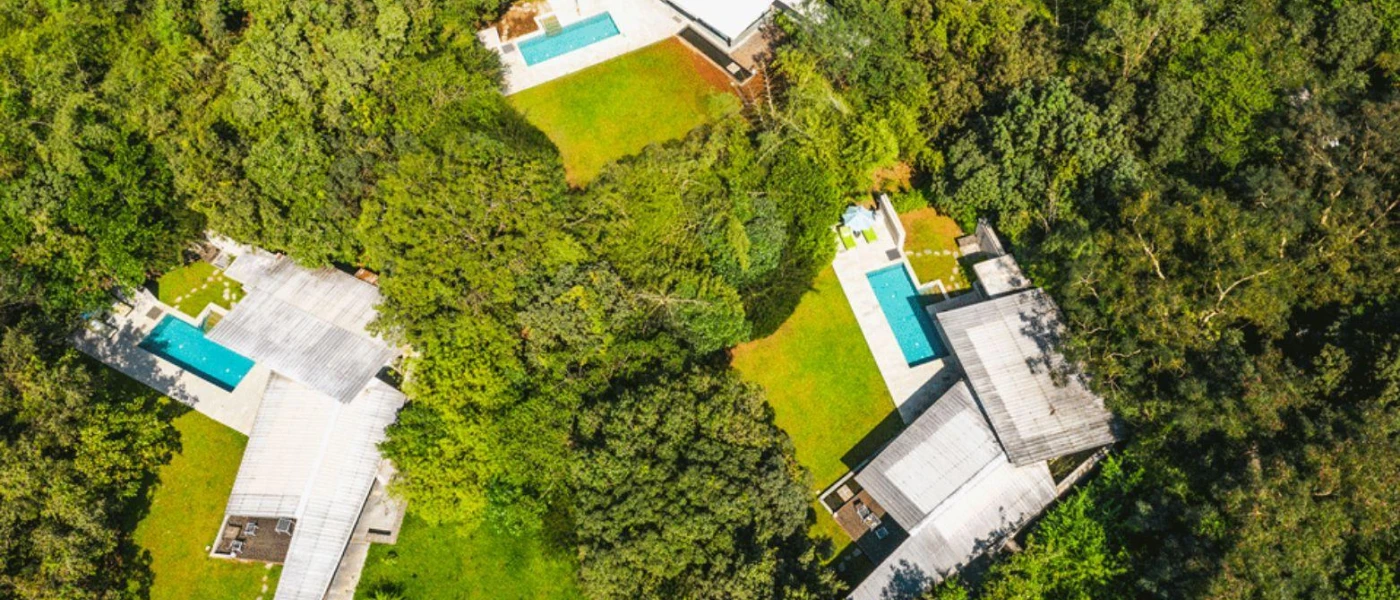 Villas with private pools among the forest as seen from the air on a sunny day