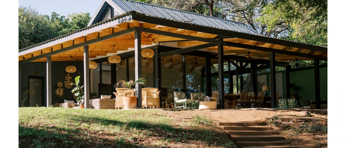 Building with outdoor seating, rattan lantern-style ceiling lights, a grassy lawn and steps down