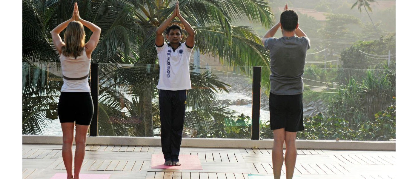 Man and woman in active wear practice yoga on a wooden deck with a glass balcony