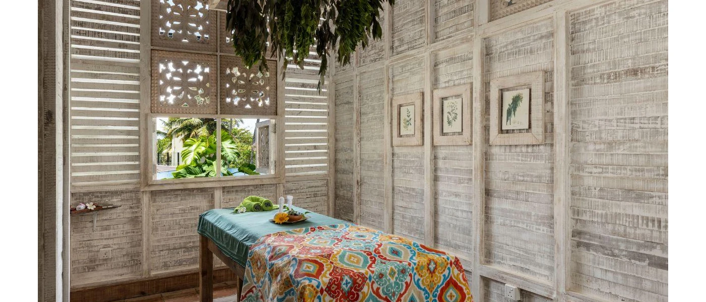 Light wood-panelled room with a massage bed with blue and multi-coloured 