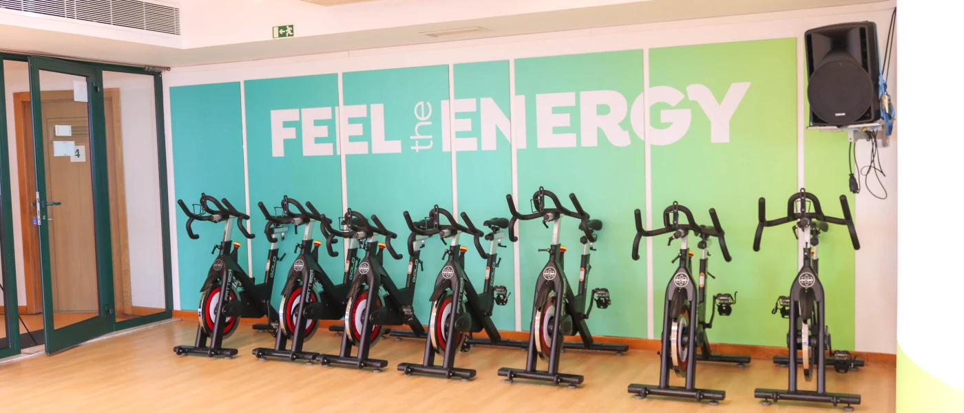 A row of exercise bikes under a turquoise wall that reads 'FEEL THE ENERGY'