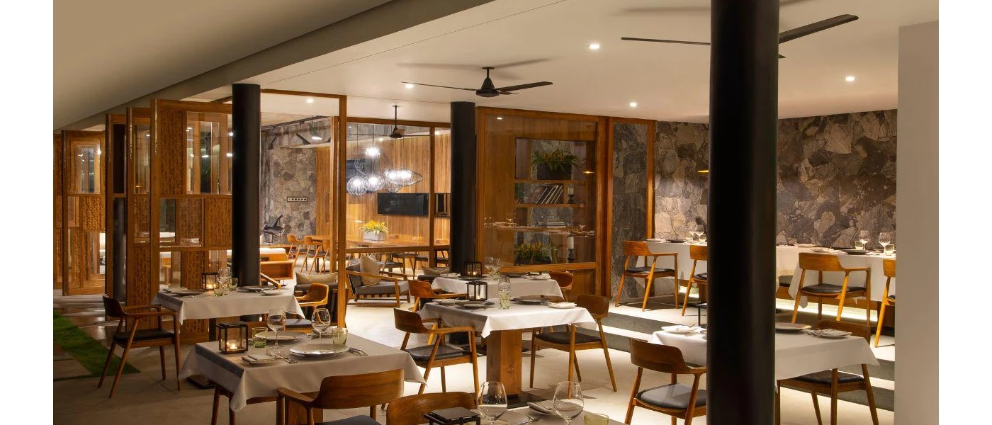 Bright restaurant with stone walls, wooden tables and white tablecloths and spotlighting