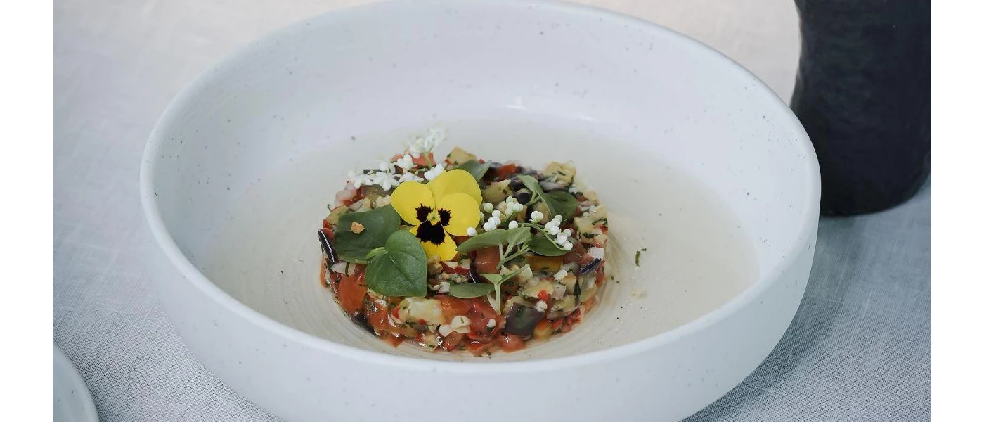 White bowl filled with healthy looking veg and grains, garnished with an edible yellow pansy