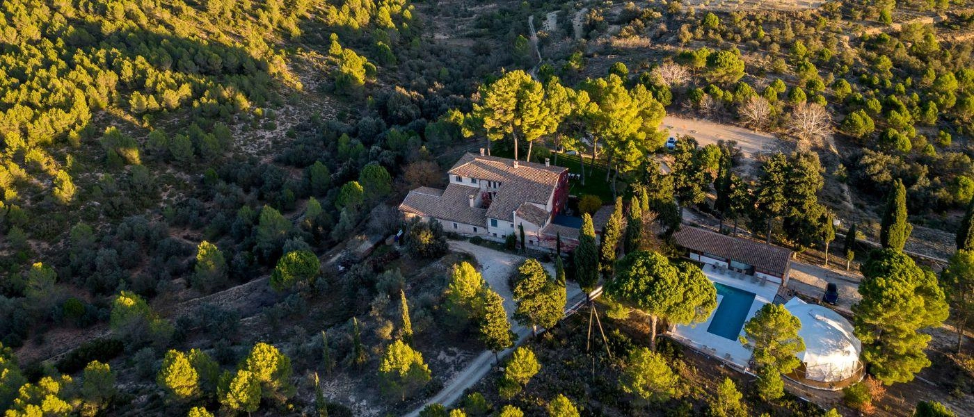 Aerial view of the main house with pool and yoga shala surrounded by woods