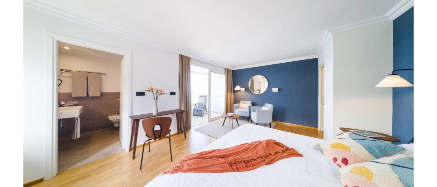 Hotel room with blue and white walls, white bedding and a terracotta throw