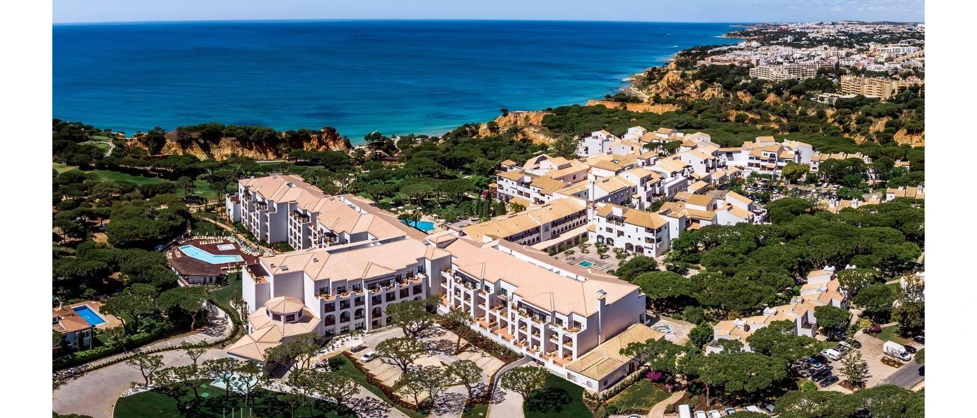 Multi-storey white resort spread among a leafy clifftop, overlooking the ocean