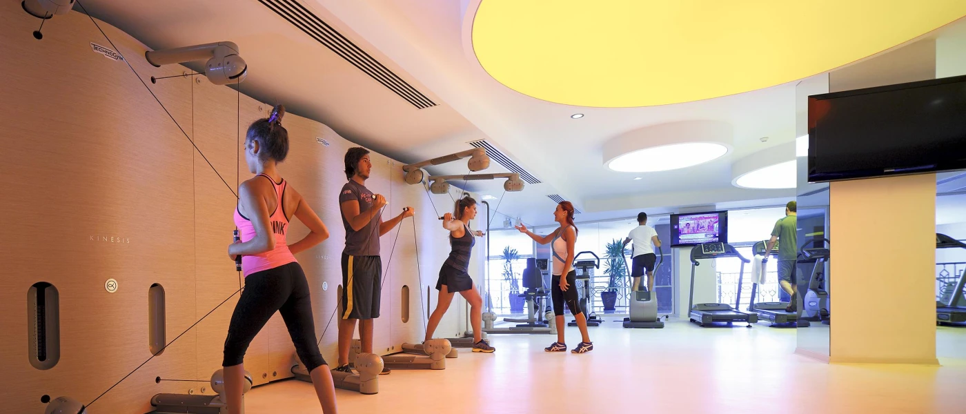 People work out using weighted ropes and treadmills in an airy gym studio