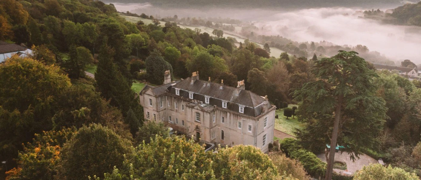 Manor house surrounded by countryside with mist in the background