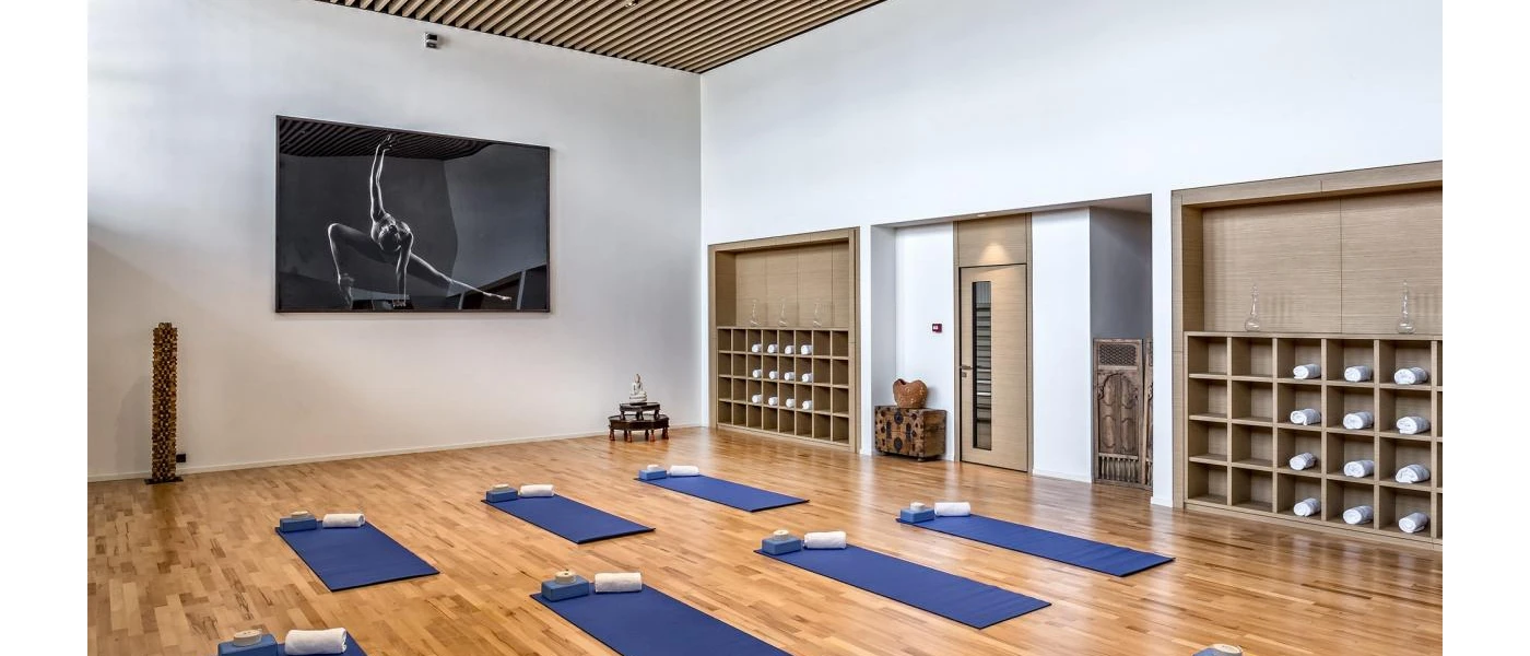Airy indoor studio with white walls and blue mats lined up in two rows and a white towel on each
